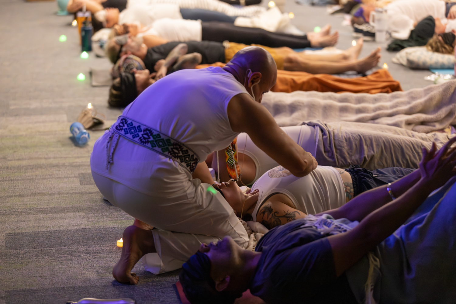 Lightbringer offering hands-on healing to participants resting in candlelight