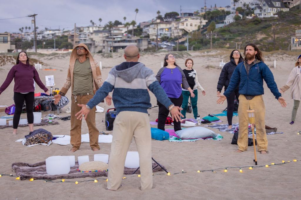 Sunset beach sound healing ceremony with community in circle