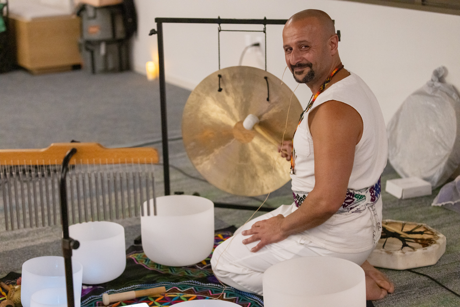 Lightbringer seated with gong and crystal singing bowls before a sound journey