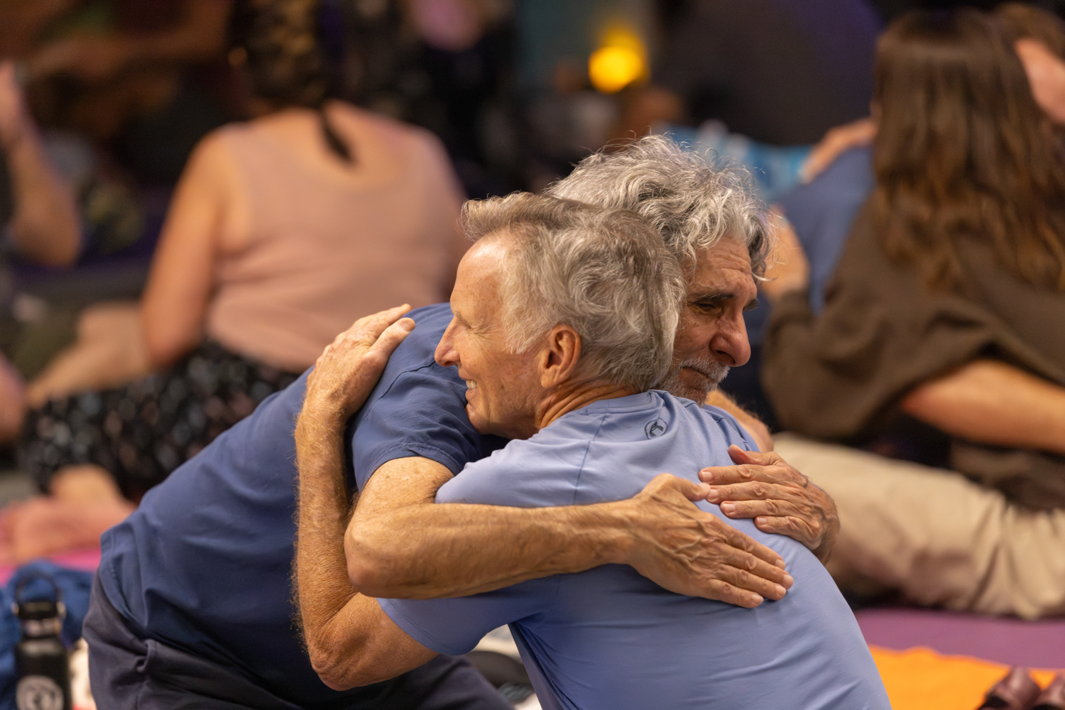 Two participants sharing a heartfelt embrace during a community gathering